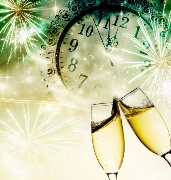 Champagne glasses, clock and fireworks at midnight