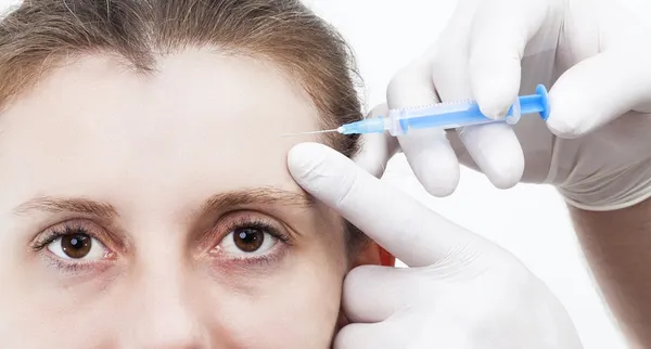 Woman getting botox injection to remove eye wrinkles