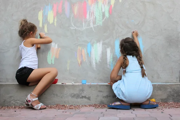 Children drawing on the wall with colored chalk