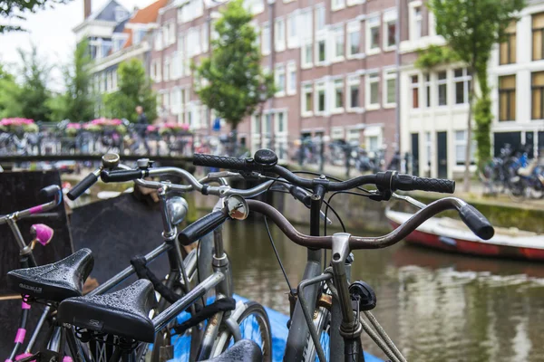 Amsterdam, Netherlands, on July 10, 2014. Bicycles are parked on the city street on the bank of the channel