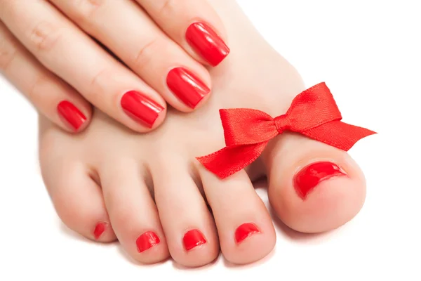 Red manicure and pedicure with a bow. isolated