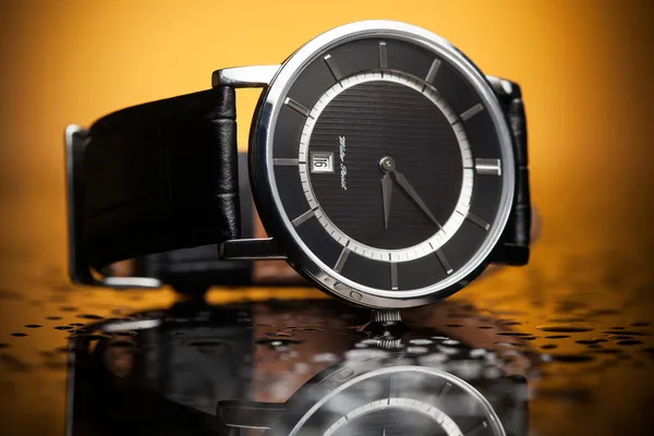 Luxury watches with a leather strap on the orange background