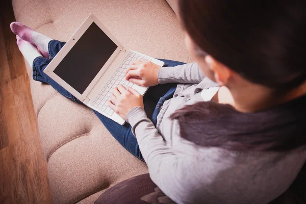 Woman is sitting on the couch with laptop