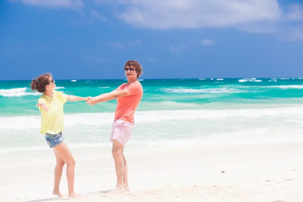 Young couple in bright clothes enjoying their time on tropical beach. holding hands