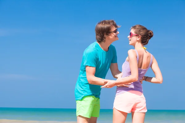 Young couple in bright clothes enjoying their time on tropical beach. holding hands