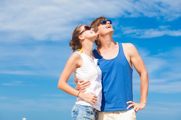 Closeup of happy young couple in sunglasses on beach smiling and looking at sky