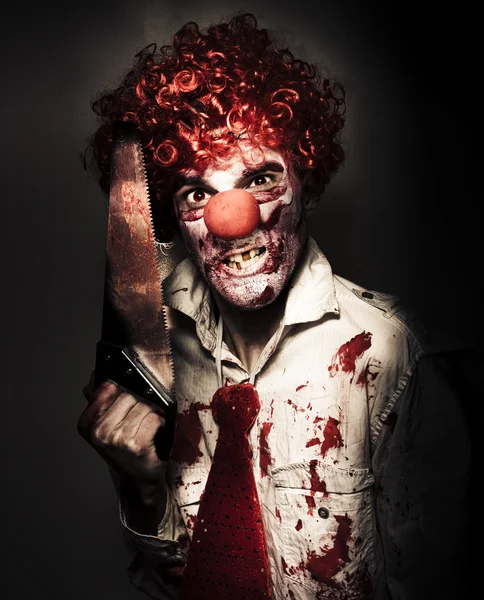 Angry Horror Clown Holding Butcher Saw In Darkness