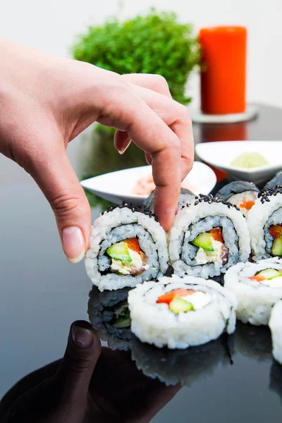 Hand holding sushi on black background