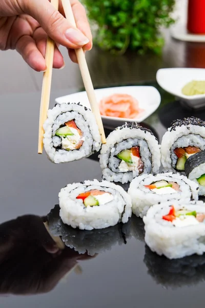 Hand holding stick with maki sushi set