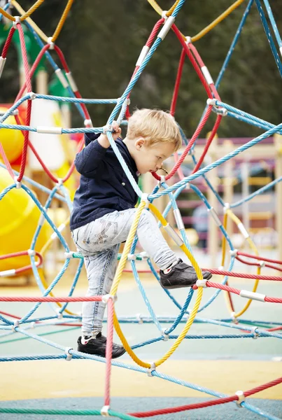 Happy little boy climbing on playground equipment
