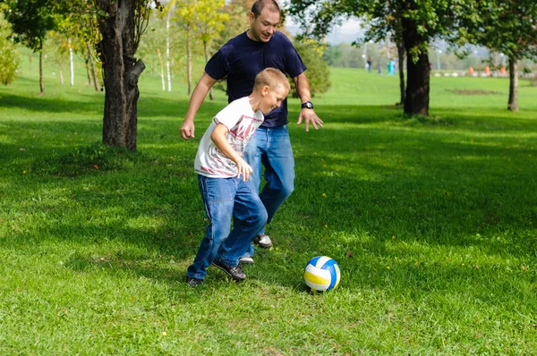 Young boy playing football with his father