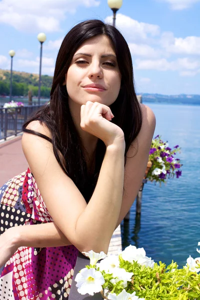 Heppy female model posing in front of flowers on a italian lake