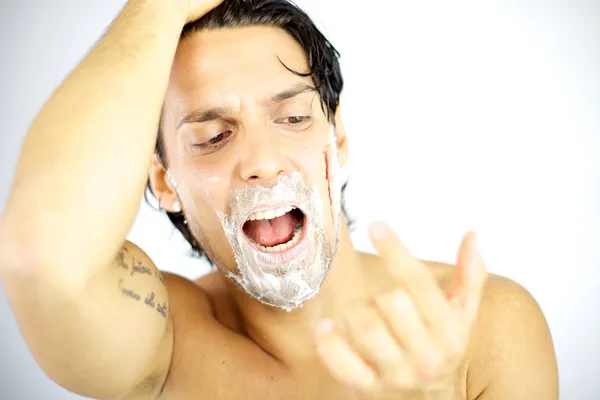 Handsome man shouting with blood on his face after shaving