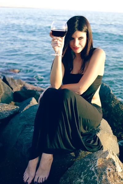 Happy woman on rocks with red wine