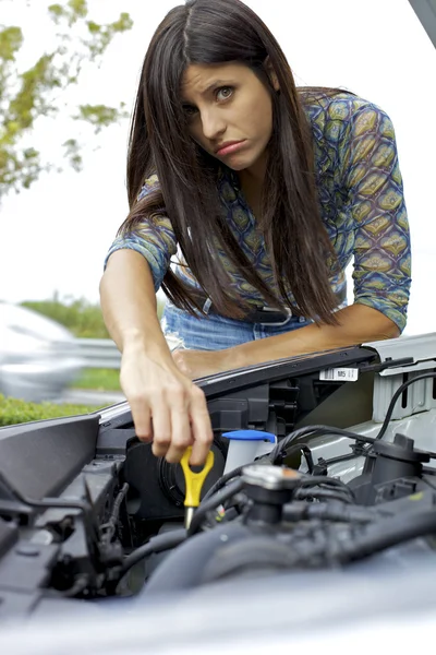 Young woman trying to fix engine of broken car