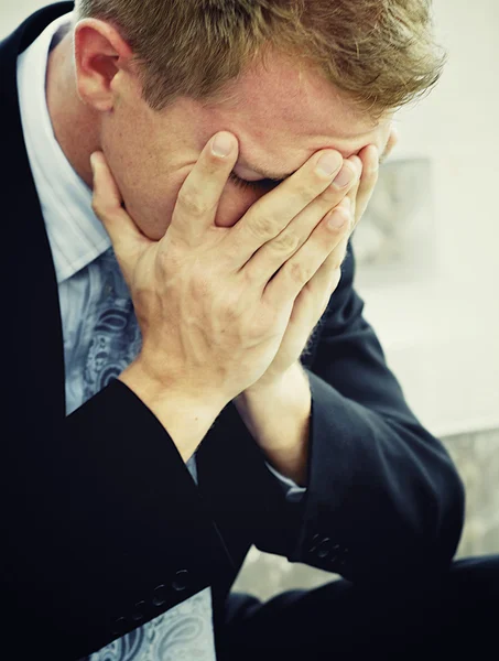 Distraught sad business man with hands in face