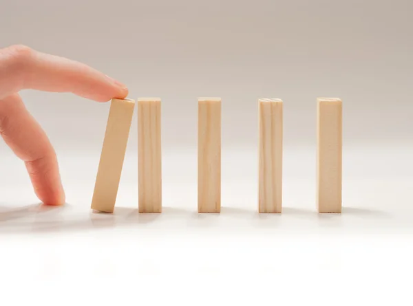 Finger colapsing wooden dominos block — Stock Photo #19450573