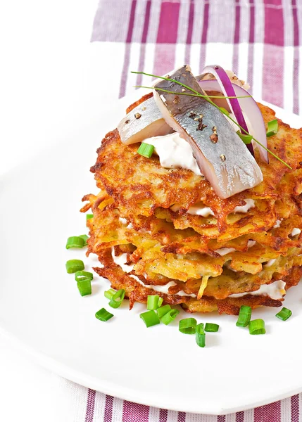 Fried potato pancakes with herring on white background