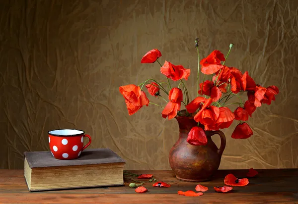 Red poppies in a ceramic vase, books and metal pots
