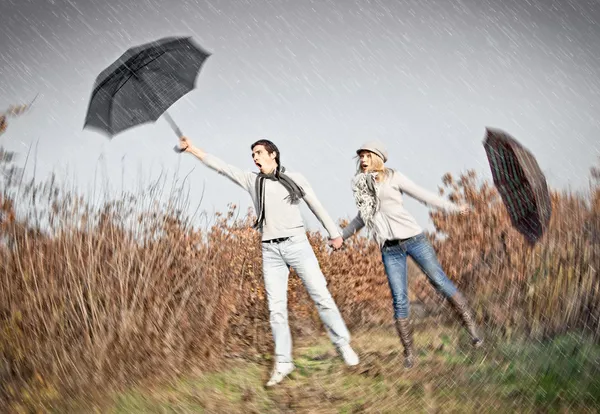 Woman and man with umbrellas during strong wind