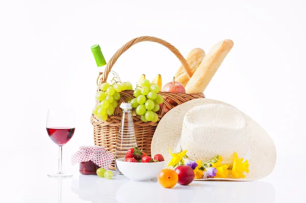 Picnic basket with bottle of wine,fruits, bread and summer hat isolated on white