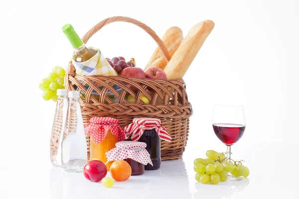 Picnic basket with bottle of wine,fruits, bread and summer hat isolated on white