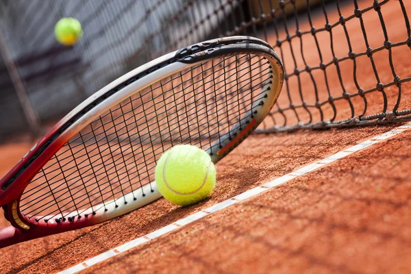 Close up of tennis racquet and balls on the clay tennis court