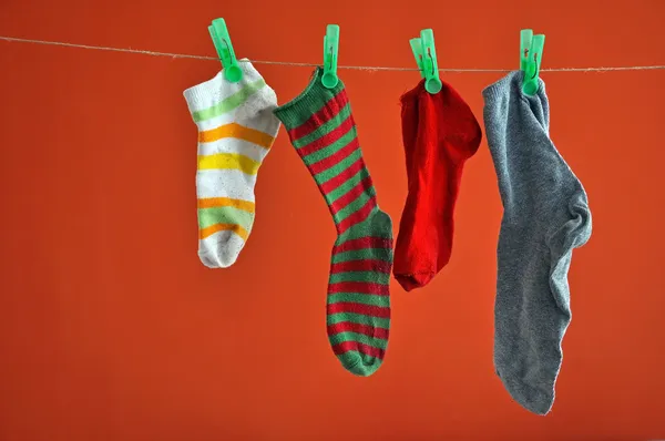 Different types of striped socks hanging on a rope isolated on red