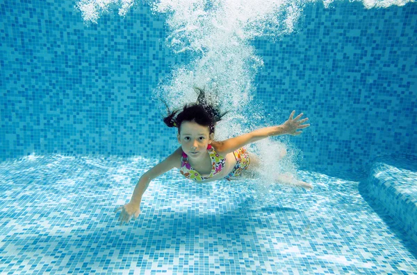 Happy underwater girl swims in pool