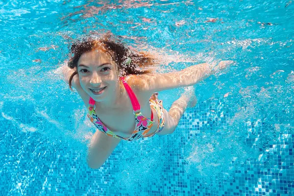 Happy underwater girl swims in pool
