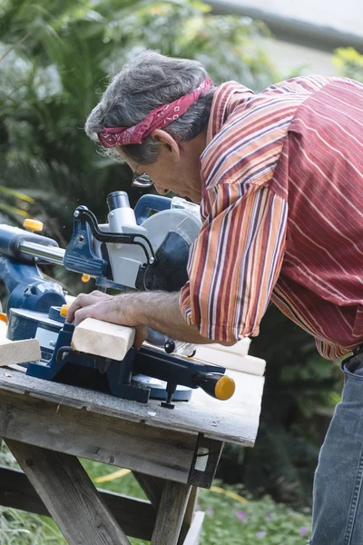 Man Sawing Wood with Sliding Compound Miter Saw