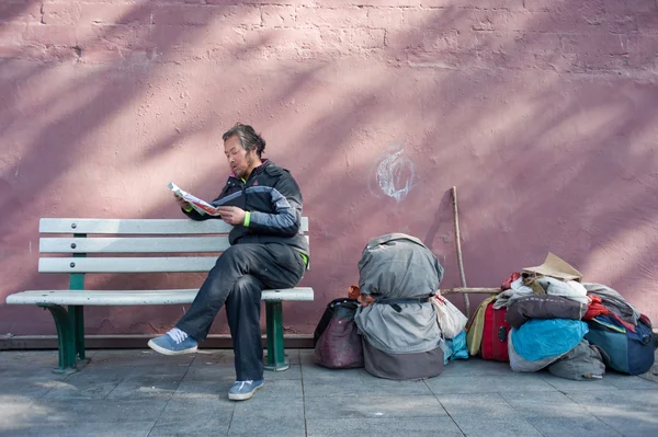 BEIJING,CHINA-April 16,, 2012: unknown to beg for old man sitting in a royal residence of the wall read, beside him lay his baggage. April 16, 2012 in Beijing\'s tiananmen square shoot,