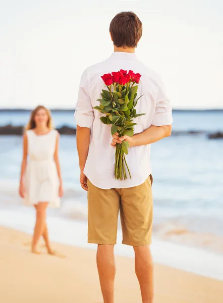 Romantic Young Couple in Love, Man holding surprise bouquet of r