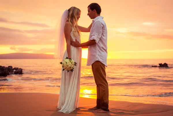 Just married couple on tropical beach at sunset