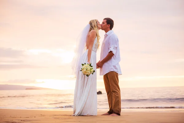 Married couple, bride and groom, kissing at sunset on beautiful