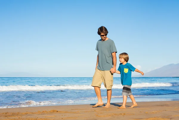 Happy father and son walking together on the beach, carefree hap