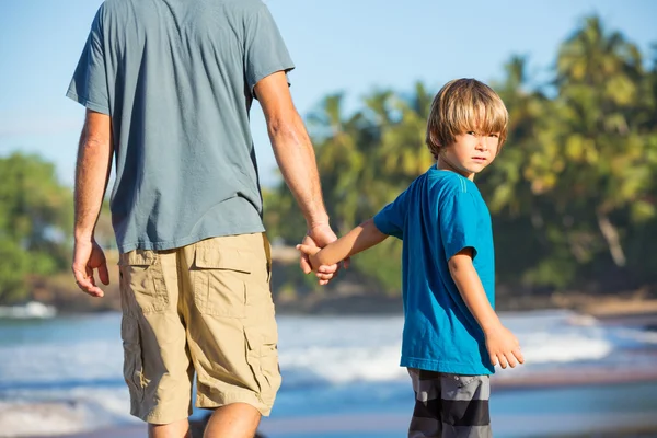 Happy father and son walking together on the beach, carefree hap