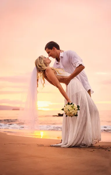 Bride and groom on beach at sunset