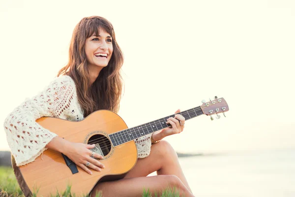 Beautiful young woman playing guitar on beach