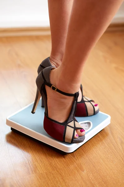Female feet in color stilettos with weight scale