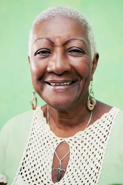 Portrait of senior black woman smiling at camera on green backgr