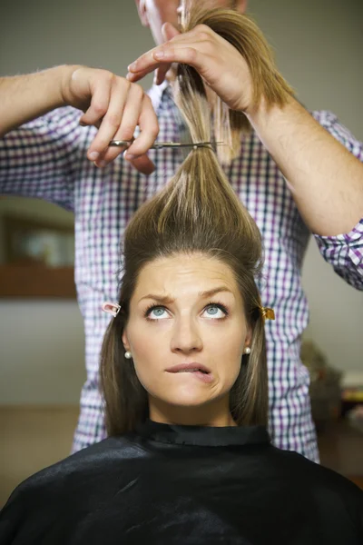 Nervous woman in hairdresser shop cutting long hair