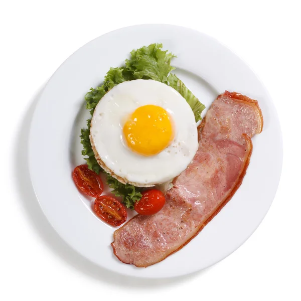 Fried eggs with vegetables and ham isolated. top view.