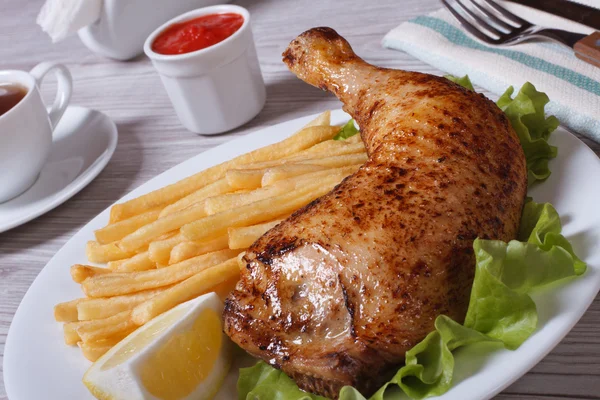 Portion of French fries with chicken leg and lemon