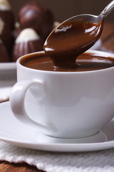 Chocolate dripping from a spoon in a cup closeup