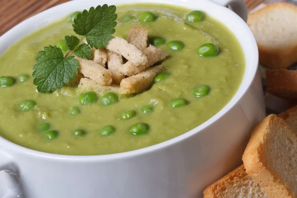 Cream soup with green peas with croutons closeup