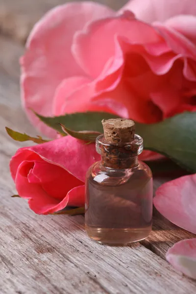 Rose water in a glass bottle on a background of pink roses