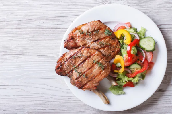 Pork meat grilled with fresh vegetable salad top view