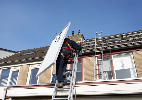 Man climbing the ladder with solar panel