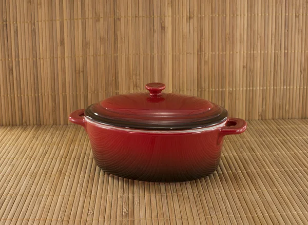 Red saucepan on bamboo